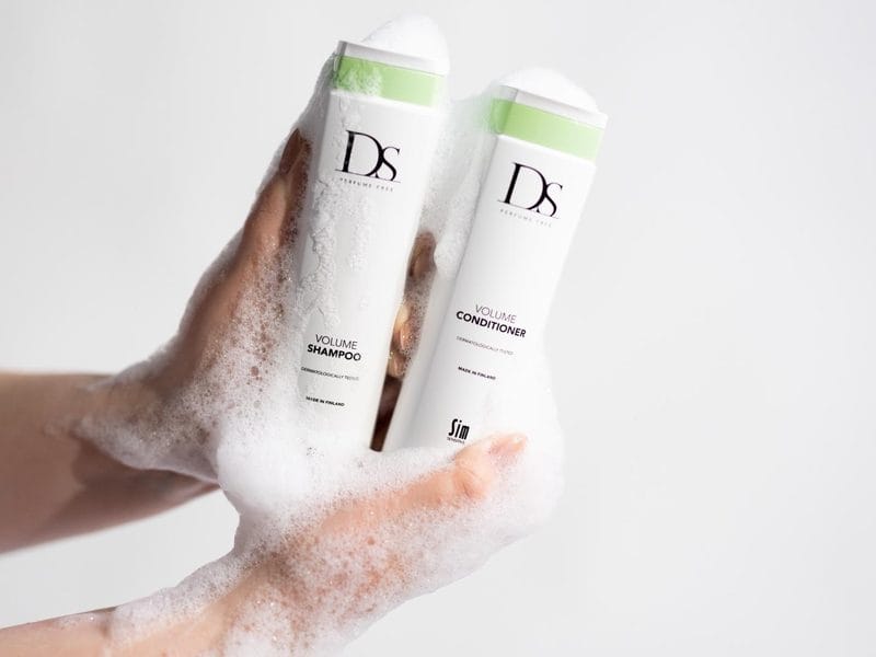 Hand med lödder som håller DS Volume Shampoo och Volume Conditioner
